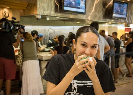 Allison eating ramen burger with Lana in the background