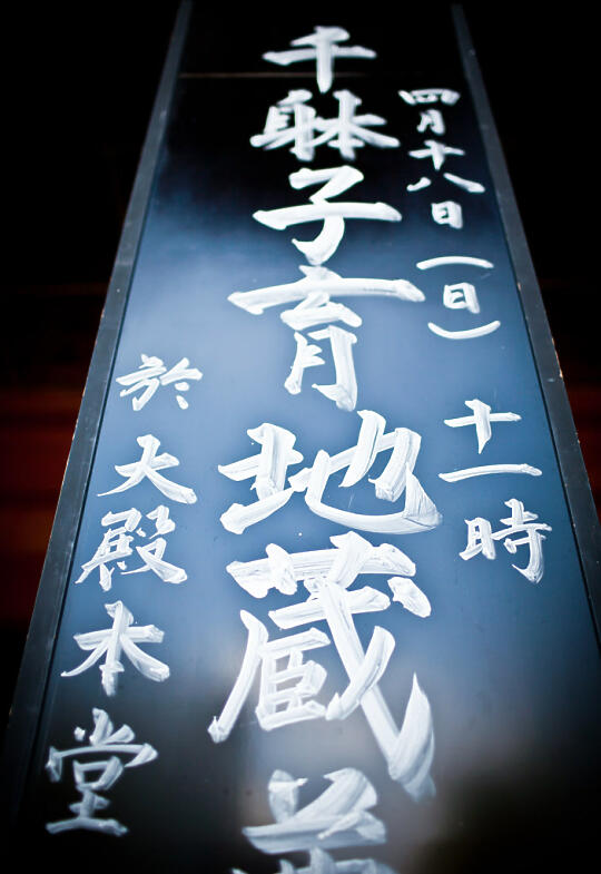 Black placard with white Japanese writing at the temple