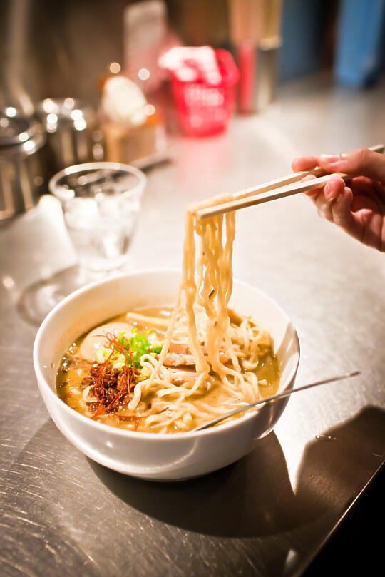 Holding up thick noodles in green curry ramen