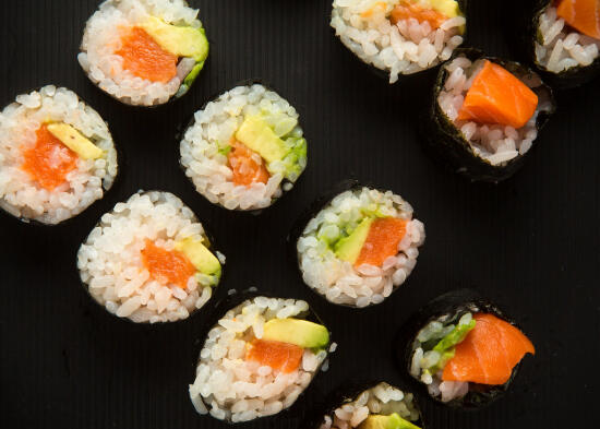 Salmon and avocado maki rolls on a black plate